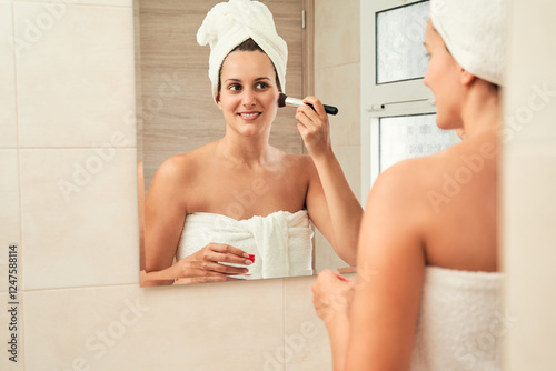 Beautiful woman applying makeup in the bathroom mirror. Skincare concept.