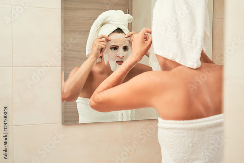 Woman applying skincare face mask in bathroom. Skincare concept.