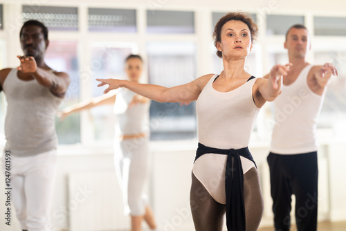 Concentrated women and men rehearsing ballet dance in studio photo