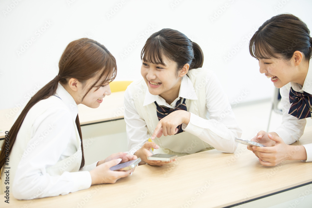 友達とスマートフォンを見ている女子高生たち 友達とスマートフォンを見ている女子高生たち