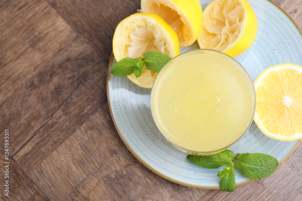 Glass of lemon juice and fresh fruits on wooden table, top view. Space for text Glass of lemon juice and fresh fruits on wooden table, top view. Space for text