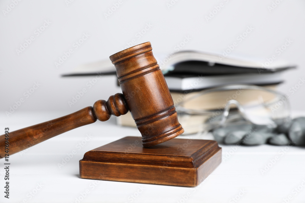 Accident at work concept. Gavel, books and construction worker's protective gear on white wooden table, selective focus Accident at work concept. Gavel, books and construction worker's protective gear on white wooden table, selective focus