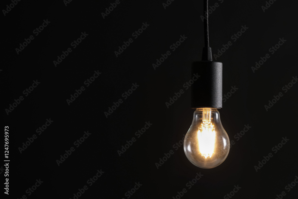 Glowing light bulb hanging on dark background. Space for text Glowing light bulb hanging on dark background. Space for text