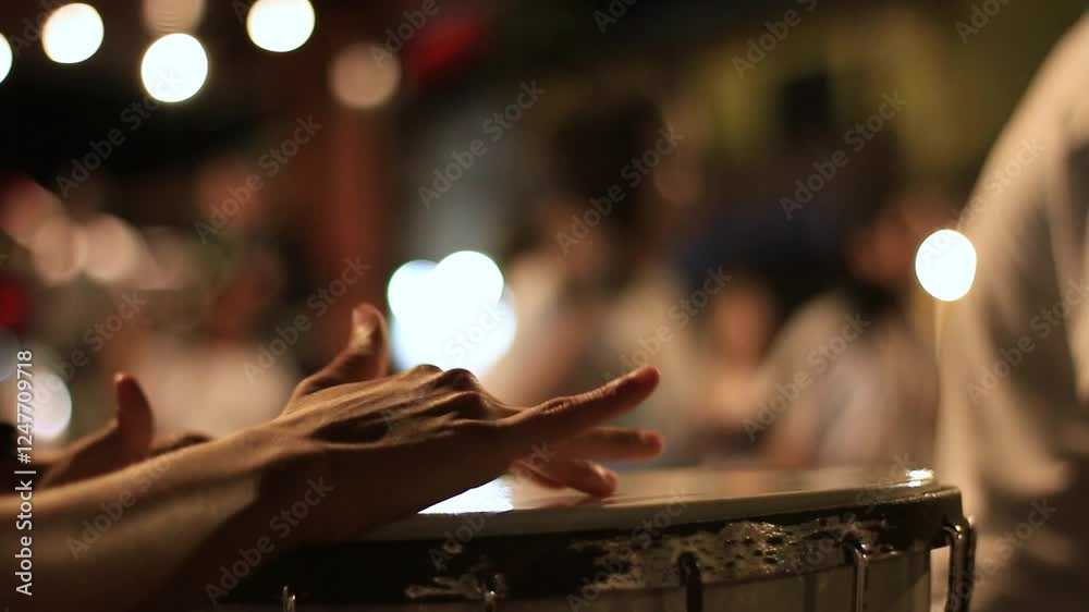 close up of hands playing metal drum percussion instrument at street concert at night