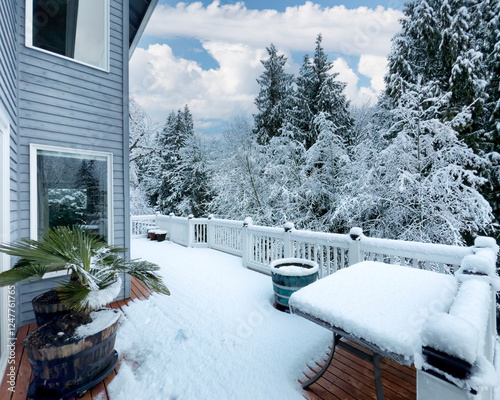 Mid winter heavy snow fallen on home deck during after storm with trees and sky