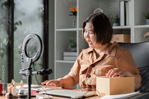 Young woman engaging her audience while livestreaming beauty cream sales from a modern home office photo