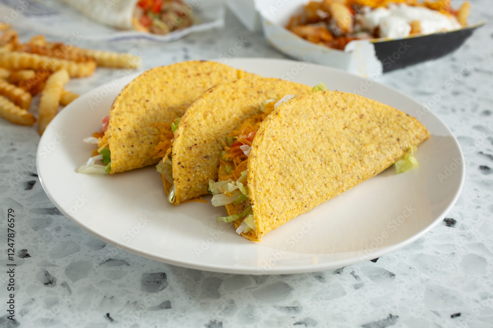 A view of three hard shell tacos on a plate. A view of three hard shell tacos on a plate.