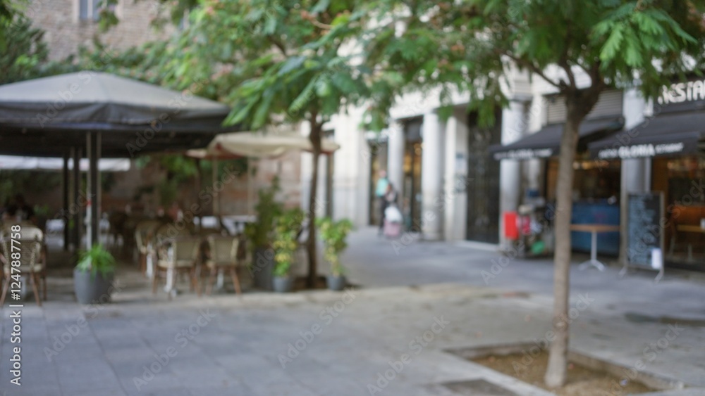 Defocused street scene in barcelona with blurred outdoor cafe seating and lush greenery under a mild bokeh effect enhancing the urban atmosphere of the european city. Defocused street scene in barcelona with blurred outdoor cafe seating and lush greenery under a mild bokeh effect enhancing the urban atmosphere of the european city.