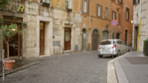 Blurry street scene in rome with defocused background and bokeh effect showing cobblestone road, old buildings, and a car outdoors in italy.