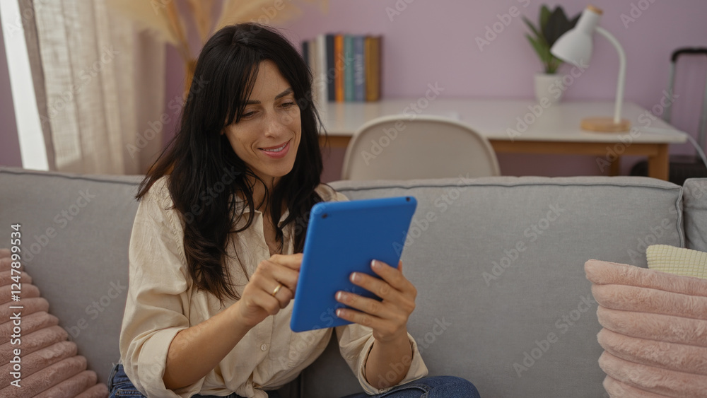 Young woman enjoying a relaxing moment in her living room, using a blue tablet, surrounded by a cozy interior setting with a sofa and bookshelf in view, evoking a sense of modern home life. Young woman enjoying a relaxing moment in her living room, using a blue tablet, surrounded by a cozy interior setting with a sofa and bookshelf in view, evoking a sense of modern home life.
