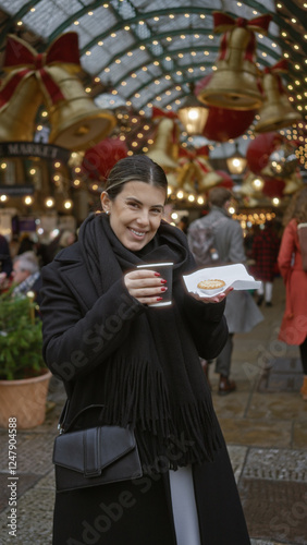 Woman joyful in london street holding coffee under festive christmas lights in covent garden surrounded by decorations and holiday shoppers smiling warmly at camera photo