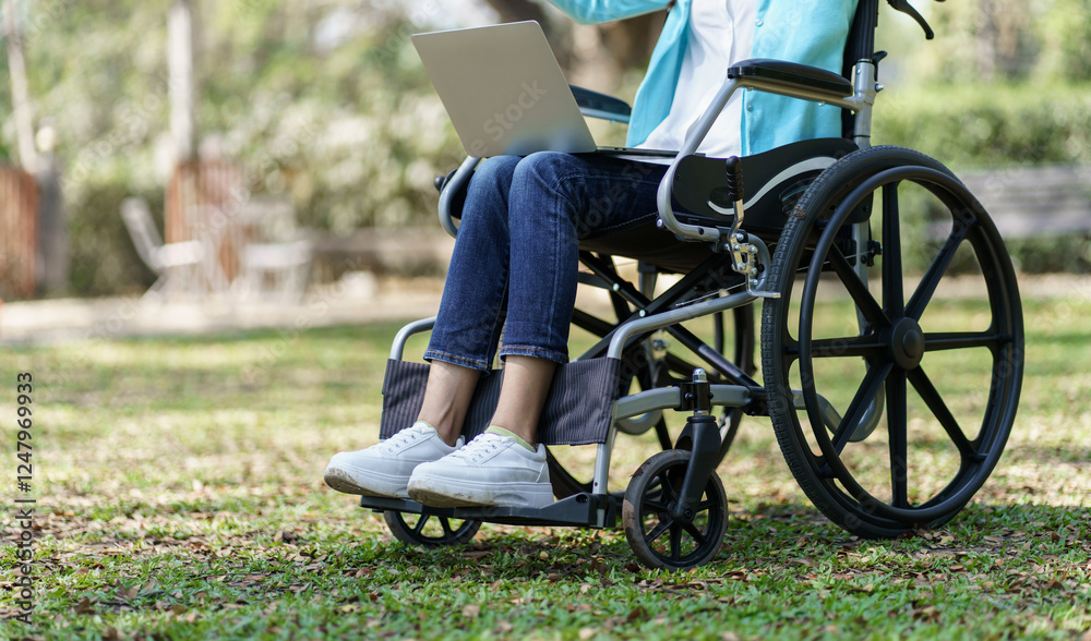 Obraz premium Young asian woman in wheelchair working with laptop