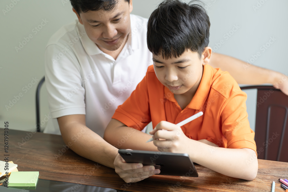 Asian father and son using tablet teaching son to draw.playing with digital tablet at desk fatherhood Asian father and son using tablet teaching son to draw.playing with digital tablet at desk fatherhood
