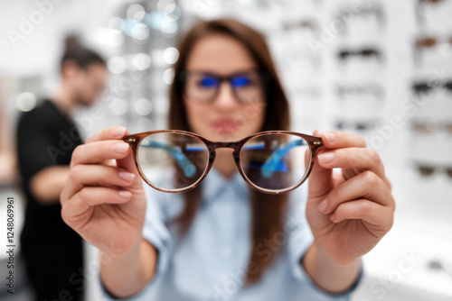 Woman at optician holding eyeglasses she wants to buy. Selective focus on glasses photo