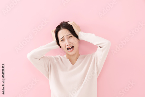 頭を抱える女性・ピンクバック
