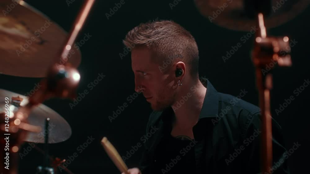 Portrait of cool drummer playing rock, handsome man beating rhythm by drumsticks . Medium shot with talented musician sitting at drum set, playing rock music on stage in concert hall, modern music Portrait of cool drummer playing rock, handsome man beating rhythm by drumsticks . Medium shot with talented musician sitting at drum set, playing rock music on stage in concert hall, modern music