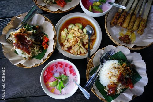 Set of nasi campur babi guling. Balinese meal of rice with Balinese roast pork and other side dishes of spicy fruit salads and mix ice. Top table view. Bali food. Indonesia food concept.