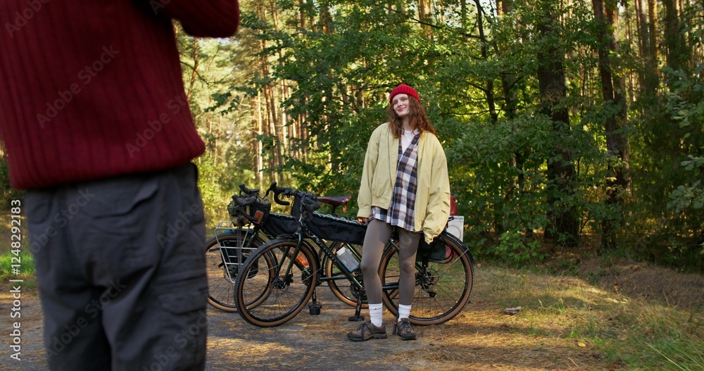 Photo shoot in the forest. A woman is smiling standing next to a bicycle. A man takes pictures with a camera Photo shoot in the forest. A woman is smiling standing next to a bicycle. A man takes pictures with a camera