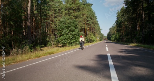 Wallpaper Mural A young couple is riding a bike on a road in the middle of the forest. Active leisure on a sunny day Torontodigital.ca