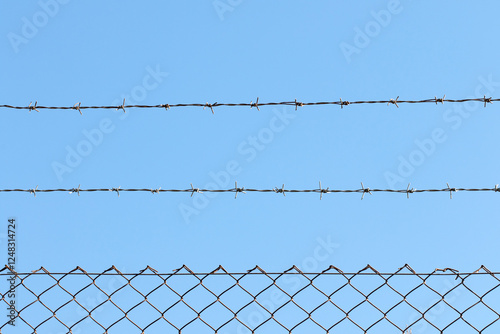 Foto A chain-link fence with barbed wire on top, constructed for security purposes along the boundary of a garden
