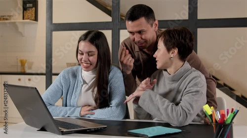 Positive attractive hearing impaired parents and pretty teenage daughter with hearing loss making video call online on laptop, communicating and sharing with relatives using sign language indoors.