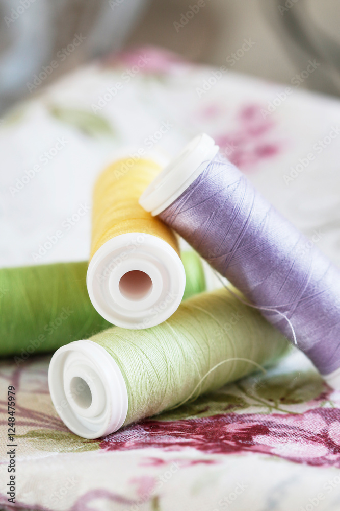 Colorful spools of thread on fabrics with floral patterns.