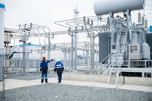 Team Electrical engineers workers inspects electrical substation with high voltage switches, wires, transformer and ceramic insulators. Concept Power plant maintenance