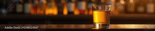 Pale yellow liquor in a short glass sits on a dark wood bar , counter, wooden photo