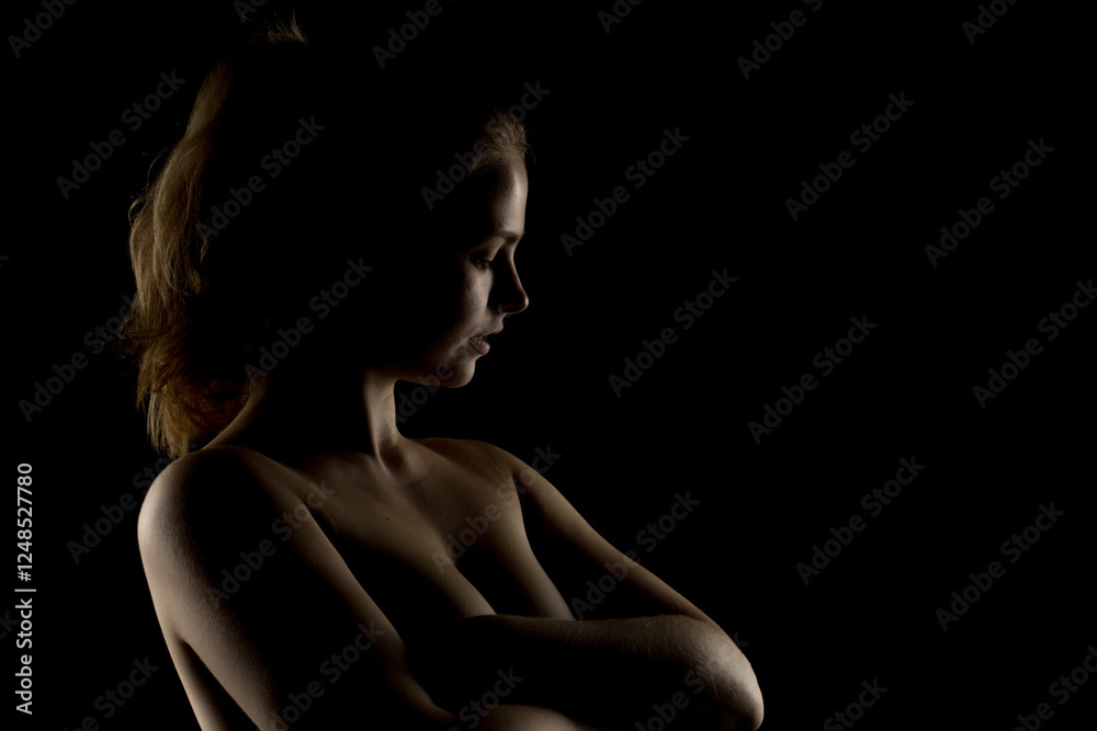 Low-key portrait of a blonde woman with head tilted back. Dramatic side lighting accentuates neck, shoulders, and arms. Silhouette effect against dark background Low-key portrait of a blonde woman with head tilted back. Dramatic side lighting accentuates neck, shoulders, and arms. Silhouette effect against dark background