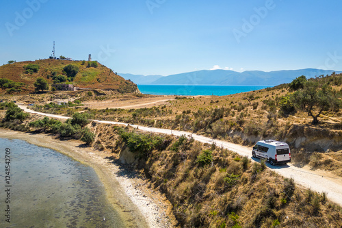 Camper van, RV or motor home is driving on gravel road from Zvernec beach or Dalan beach near Vlore, Albania