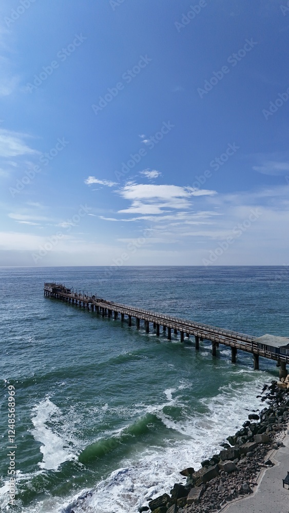 Jetty-pier stretching into deep blue ocean with clear blue sky above Jetty-pier stretching into deep blue ocean with clear blue sky above
