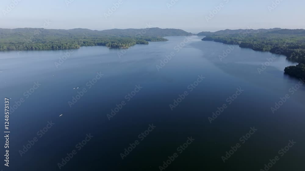 Expansive aerial shot of Presa Rincón reservoir with calm waters and lush green hills in the Dominican Republic