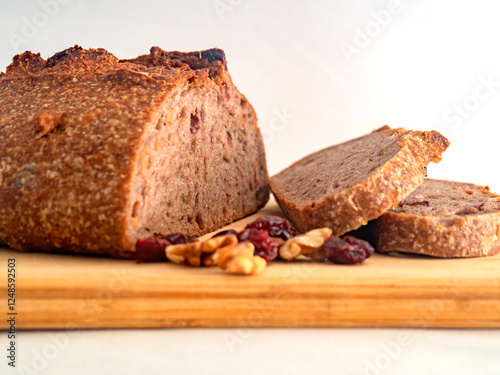 Pan de masa madre perfectamente horneado con nueces y arándanos, presentado sobre una tabla de madera / Perfectly baked sourdough bread with walnuts and cranberries, presented on a wooden board