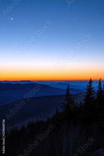 A person stands on a mountain, watching a beautiful sunset