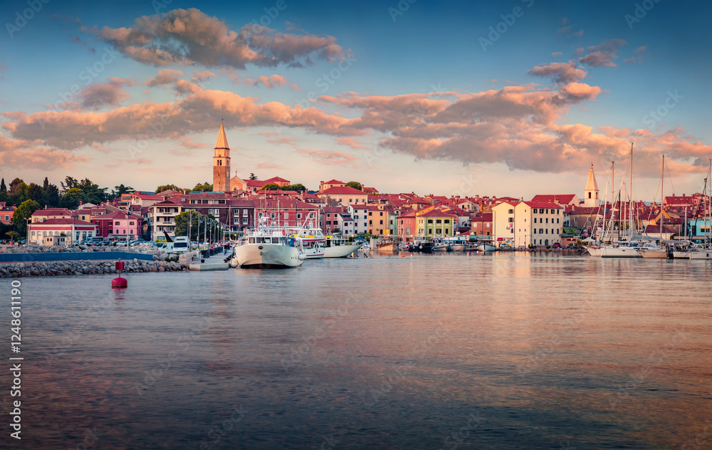 Fototapeta premium Stunning evening cityscape of old fishing town - Isola. Wonderful summer seascape of Adriatic Sea. Amazing sunset in Slovenia, Europe. Traveling concept background.