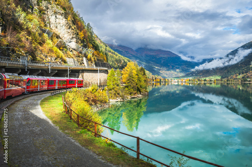 Red Train on Bernina Express Route Along Lake Miralago in Swiss Alps, Val Poschiavo in the canton of Graubunden, Switzerland. photo