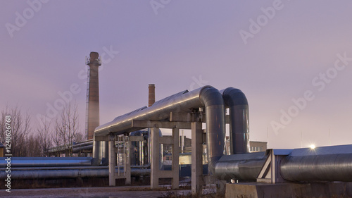 pipeline in industrial zone at night with factory buildings in the background