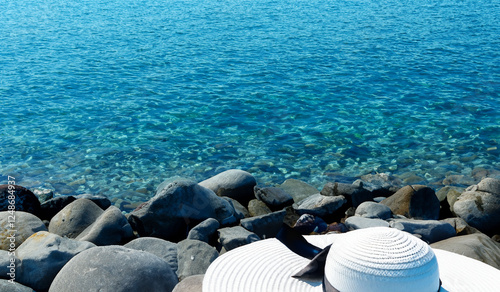 Calm clear blue sea water stones beach seascape with white sun hat on the rock beauty of nature landscape lifestyle background 