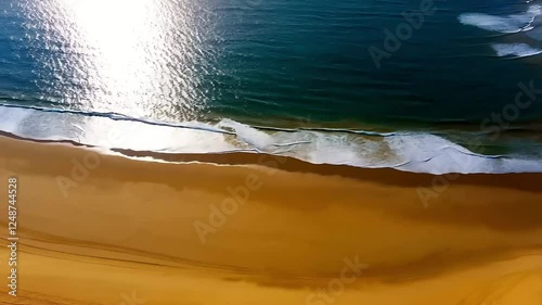 A high-angle landscape showing waves washing onto a sandy shore for natural background