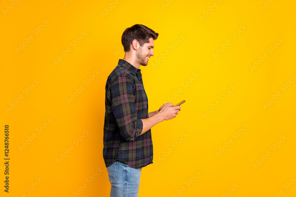 Profile photo of blogger guy holding telephone in hands checking instagram followers wear casual plaid shirt isolated yellow color background Profile photo of blogger guy holding telephone in hands checking instagram followers wear casual plaid shirt isolated yellow color background