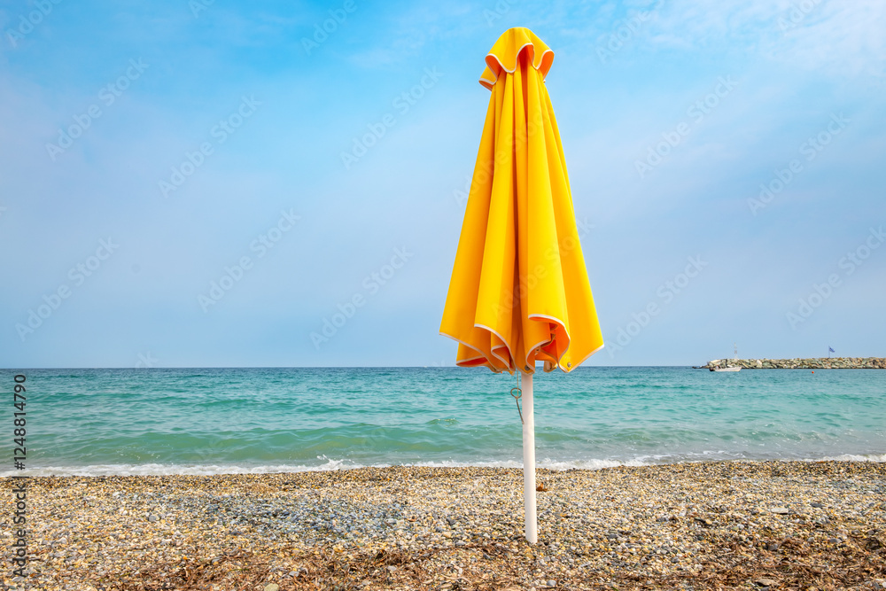 Yellow umbrella on pebble beach. Greece
