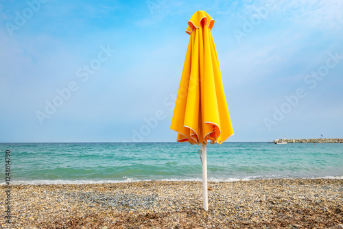 Obraz na płótnie Yellow umbrella on pebble beach. Greece w salonie