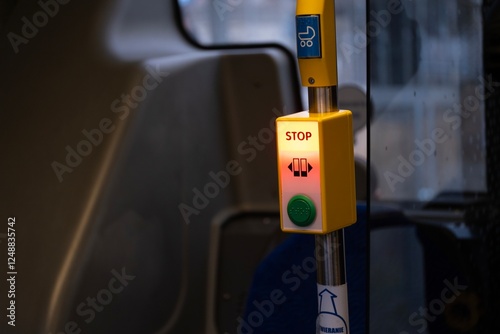 Wallpaper Mural A close-up of an illuminated stop button inside a public bus. The yellow panel with a red-lit STOP sign and a green button is mounted on a metal pole, indicating a request to stop the vehicle. Torontodigital.ca
