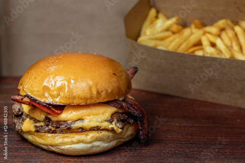 burger sandwich with cheese and bacon and french fries blurred in the background