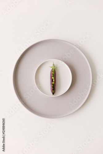 Marrow fat peas still in their skin lying on a small plate.