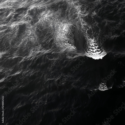 Black and white photograph of ocean waves. Aerial view, dark shore, crashing waves, deep black sea. Top view, abstract background.