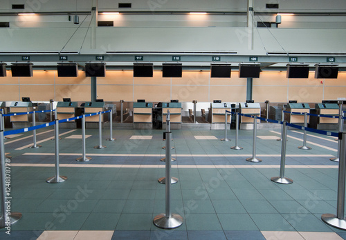 An airport check in area, closed desks and empty wait line queuing spaces.