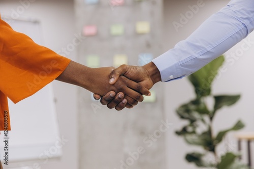 Two african american professionals shaking hands in a modern office, representing successful collaboration and diversity in the workplace photo