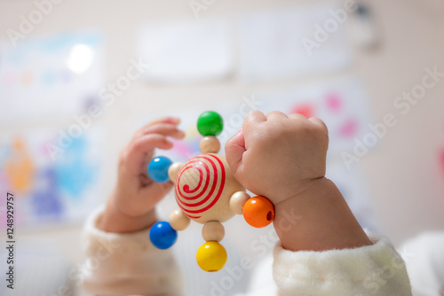An infant baby hands holding and  playing with a wooden teether toy photo
