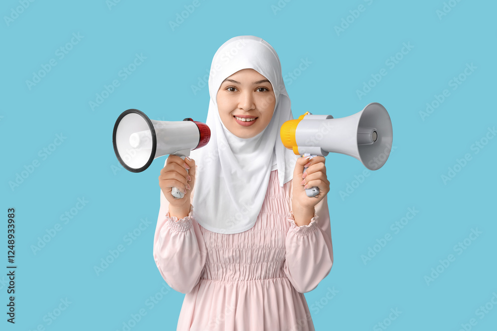 Young Asian Muslim woman with megaphones on blue background. National Be Heard Day Young Asian Muslim woman with megaphones on blue background. National Be Heard Day